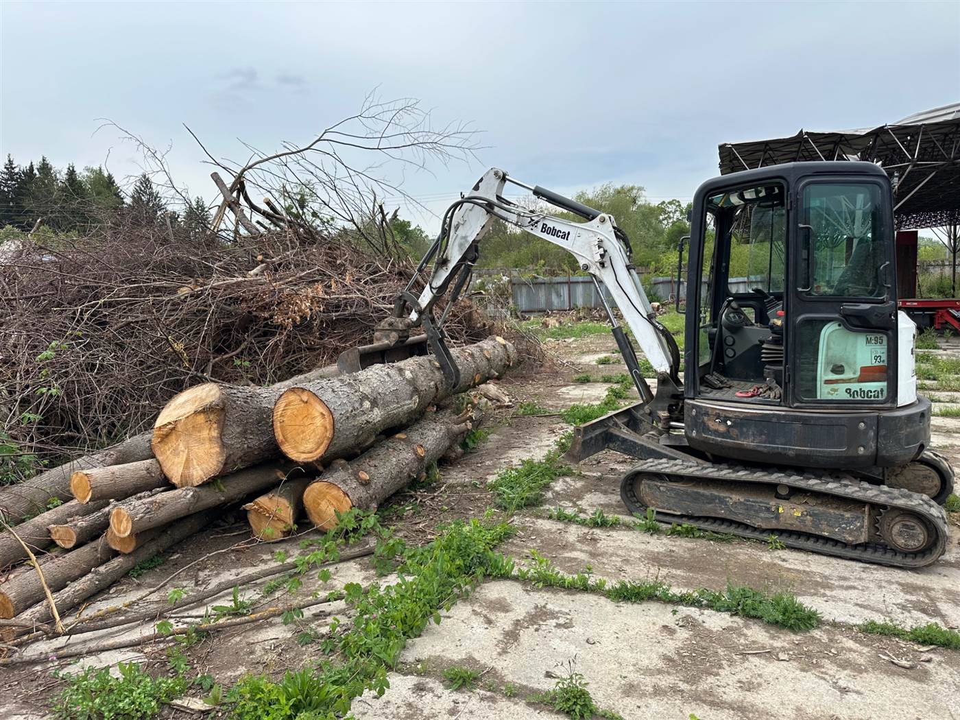 Minibager Bobcat E26 pri manipulácii s drevom